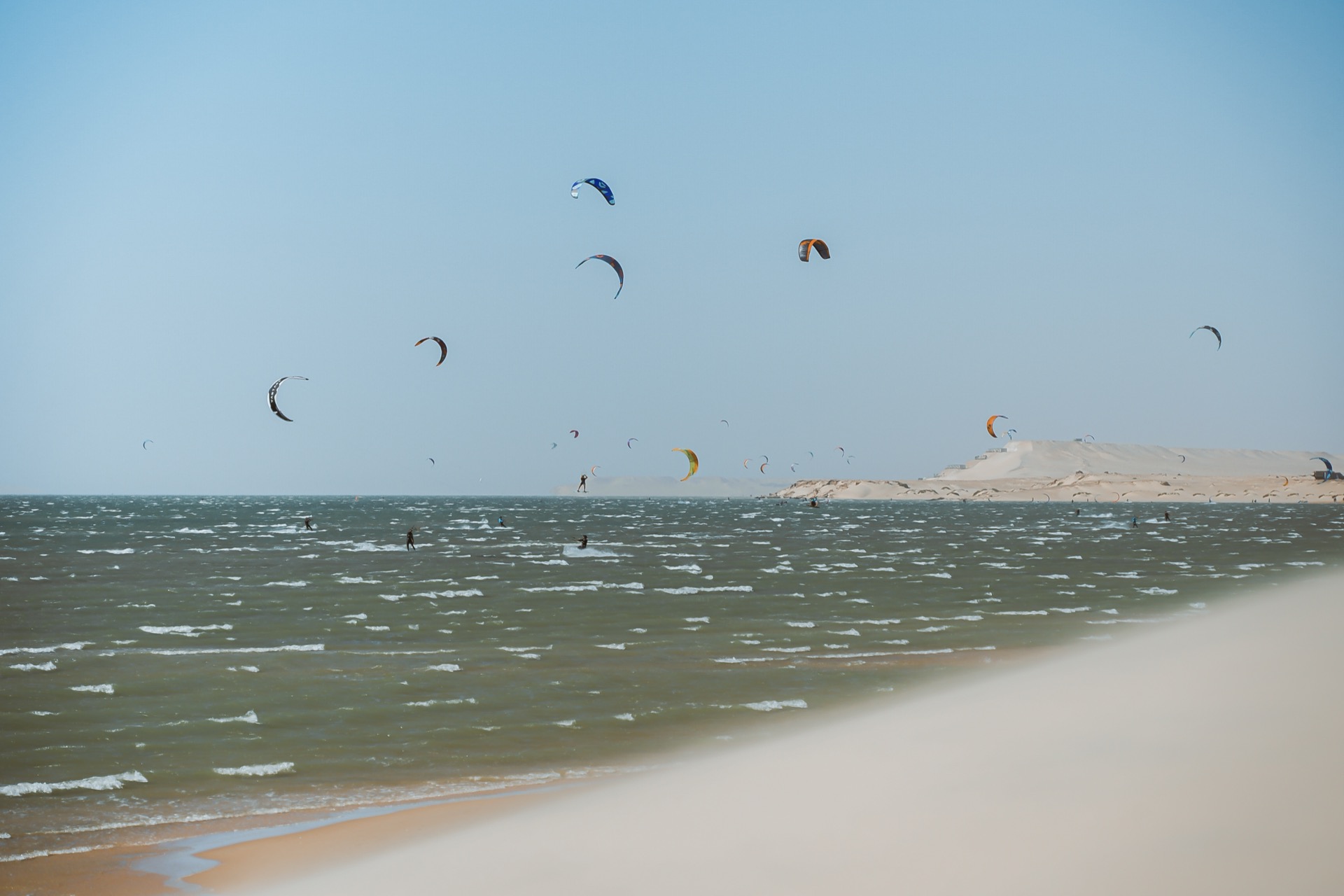 Colorful kites filling the sky over Dakhla's beach with white dunes in background